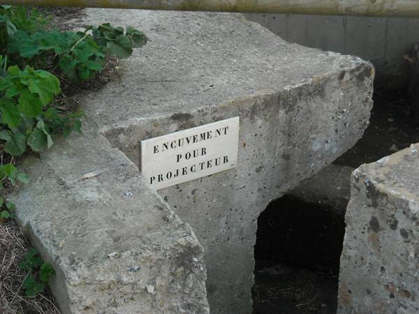 Concrete bunker with French sign 'encuvement pour projecteur', natural daylight