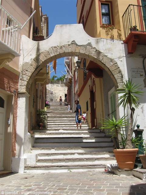 Stone arch over white steps between colorful houses, woman and child descending