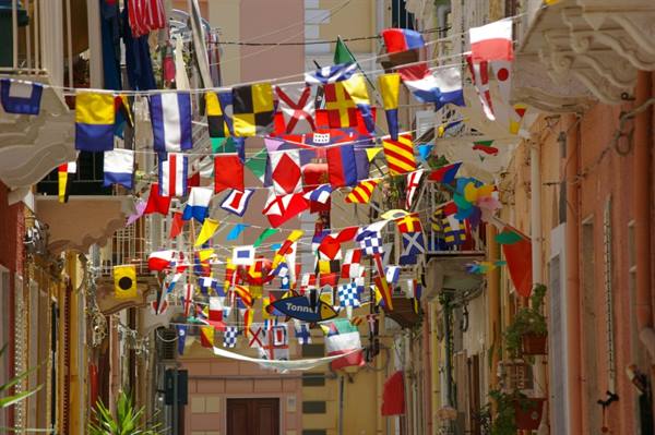 Colorful nautical flags strung between balconies and pastel houses in a narrow alley