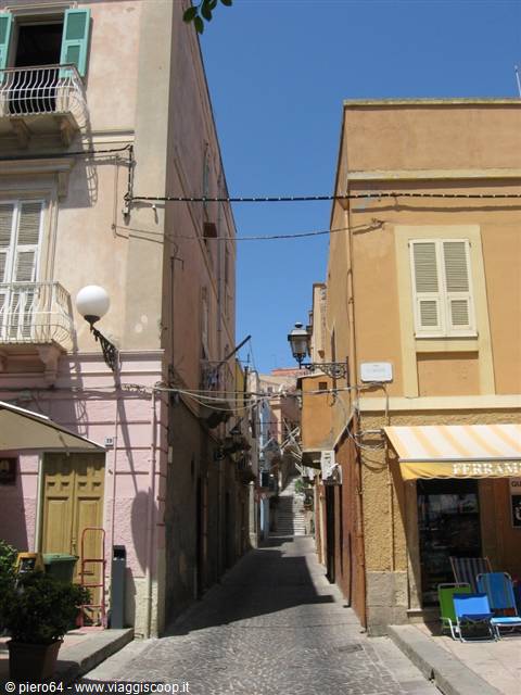 Cobbled alley between ochre and pink houses with balconies, blue sky