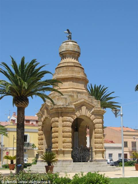 Stone monument with dome and statue, palm trees under blue sky, Carloforte