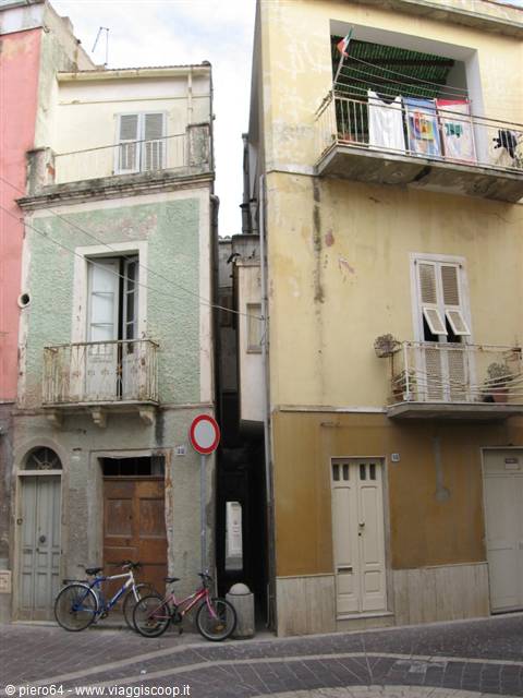 Bicycles parked between old colorful buildings with balconies and hanging laundry
