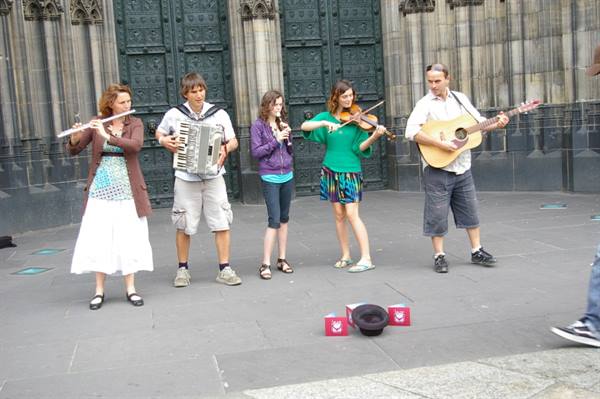 Street musicians play flute, accordion, violin and guitar in front of Cologne Cathedral