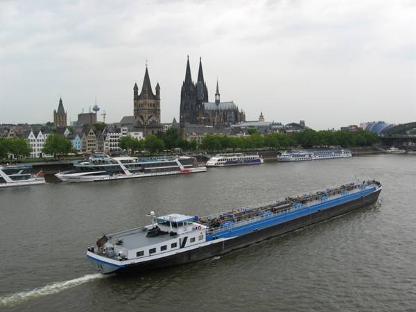 Blue barge on the Rhine in front of Cologne Cathedral under cloudy sky