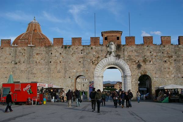 Porta a Mare gate in Pisa: crenellated brick walls, marble arch, people passing beneath