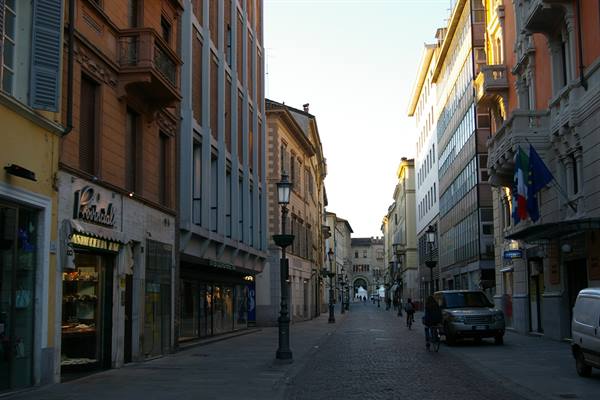 Pedestrian street with Italian and EU flags toward the old gate