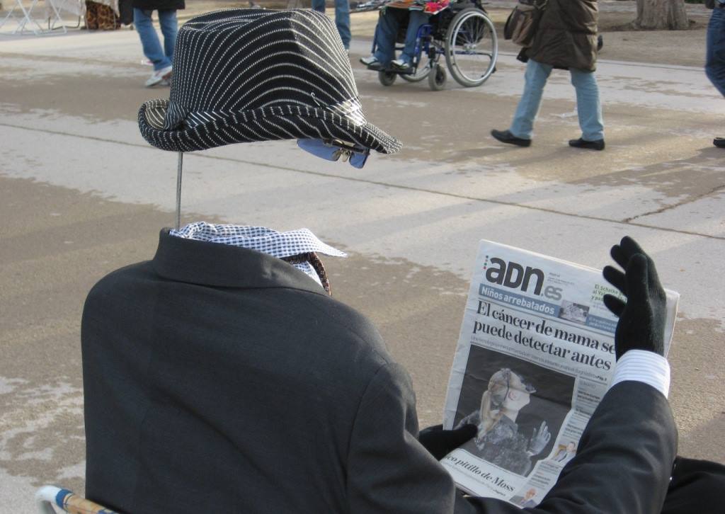 Statua manichino invisibile con cappello a righe legge giornale adn in piazza