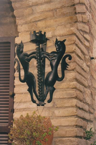 Wrought iron candle sconce with two rampant cats on stone wall