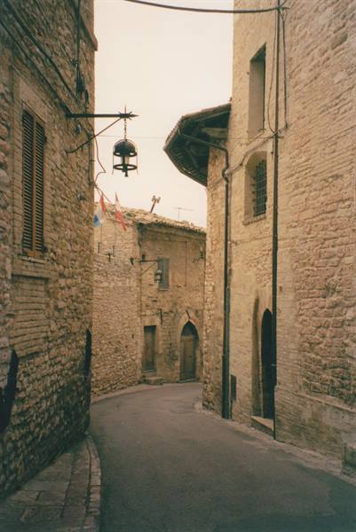 Narrow medieval stone alley, hanging lantern, empty curving lane between old buildings