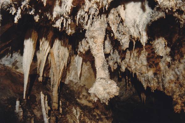 Limestone stalactites and formations inside a cave, lit artificially