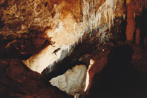 Limestone stalactites in cave, warm light on rock walls