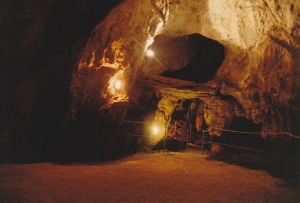 Cave lit by lamps, rocky walls and roped walkway