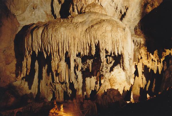 Limestone curtain formation with stalactites lit inside a karst cave