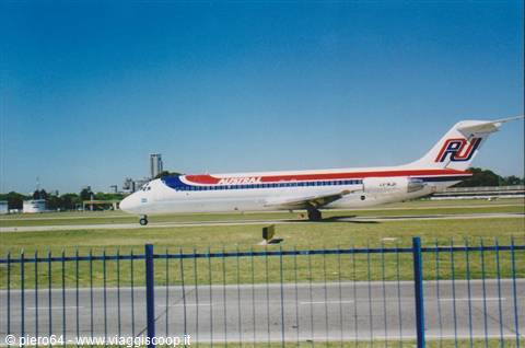 Austral jet with red and blue livery taxiing on grass near the runway