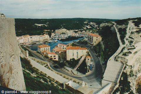 Bonifacio harbour with boats, ochre houses and white limestone cliff rampart