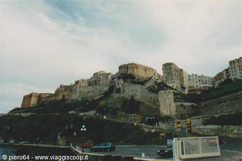 Limestone fortification walls rising above the road, cloudy sky over Valletta