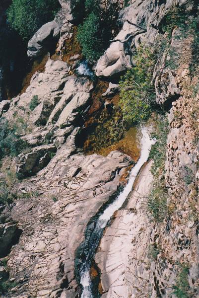 Stream cascading over smooth granite rocks among Mediterranean shrubs