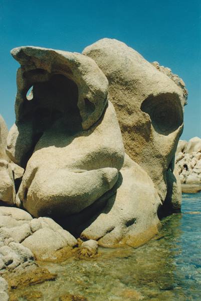 Wind-sculpted granite rocks over clear water at Capo Testa