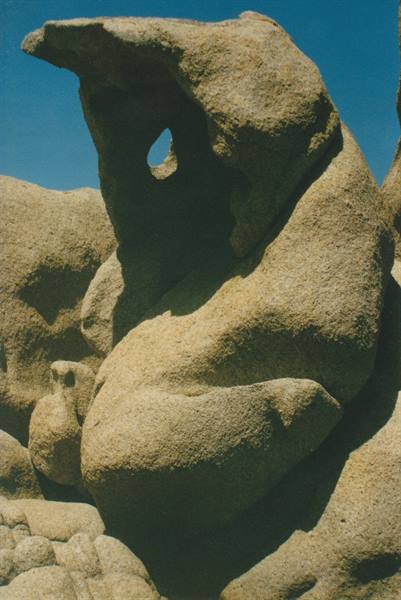 Eroded granite rock with natural hole, harsh sunlight against blue sky