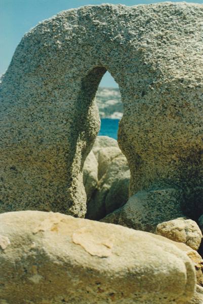 Eroded granite rock with natural hole, blue sea behind