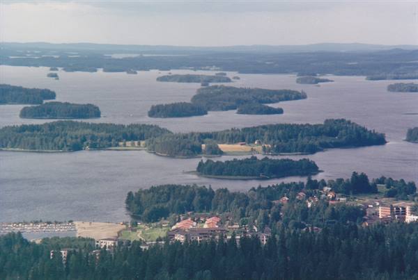 forested islands across a wide lake, village with red houses below