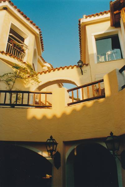 Wooden balconies and yellow arches in sunlight, Porto Cervo