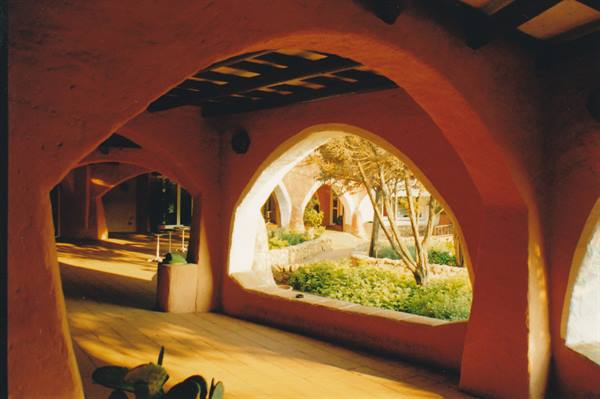 Red plaster arches porch, golden light over the garden