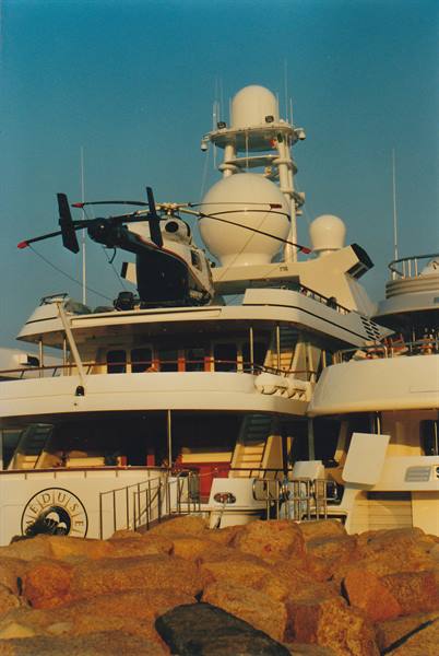 Helicopter on Meduse yacht deck among radar domes and granite rocks