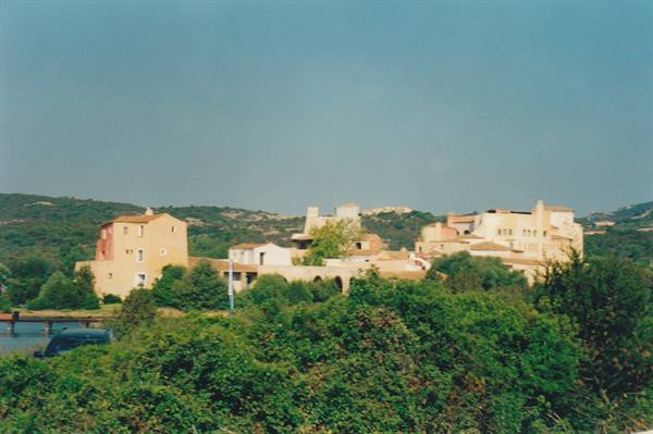 Colorful Mediterranean villas among green shrubs, hills in the background