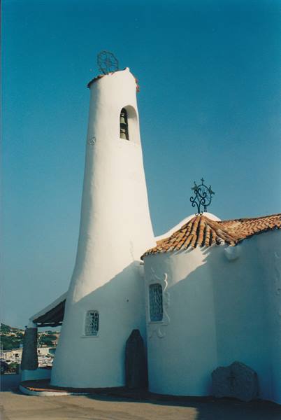 Curved white bell tower with bell, terracotta roof tiles, wrought iron, blue sky