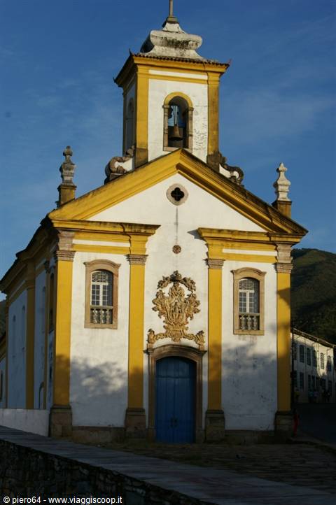 Colonial church in white and yellow with bell tower and blue door