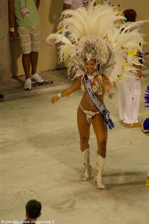 Samba dancer in white feather headdress and sequins parading at night