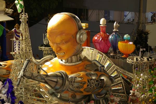 Carnival float with giant orange robot head and colorful perfume bottles