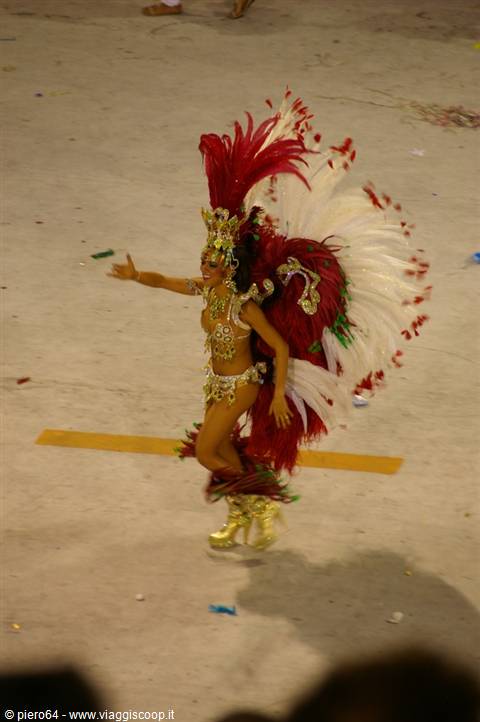 Samba dancer in red feathers and golden costume parading at carnival