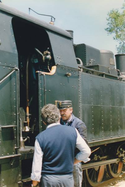 Two men beside a green steam locomotive, one wearing a driver's cap