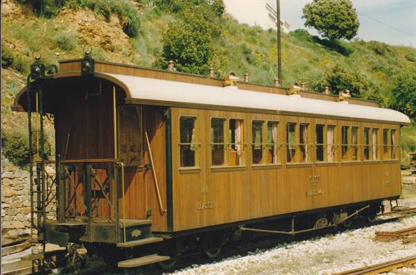 Wooden vintage passenger coach with balcony, on tracks among green hills