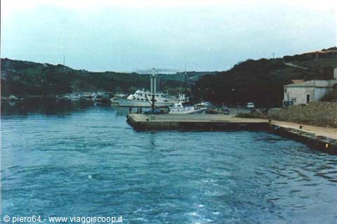 Concrete pier with moored yachts in the harbour, green hills around
