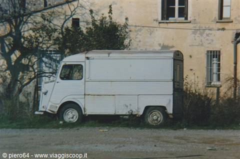 Rusty white Citroën van parked in front of a yellow house