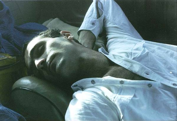 Man sleeping on a leather armchair, white shirt, harsh sunlight