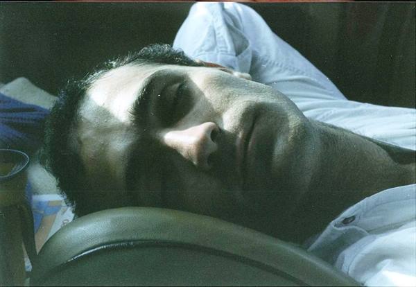 Man sleeping against a leather chair, sunlight on his face