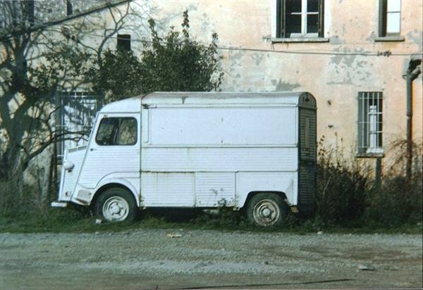 Rusty white Citroën van parked in front of an old house with peeling plaster
