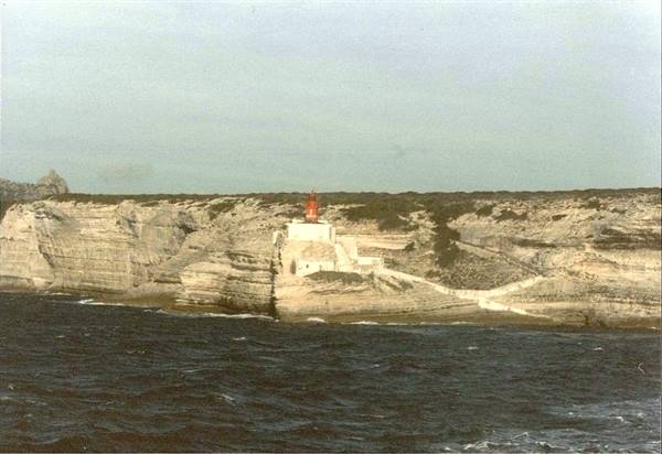 Red lighthouse on Bonifacio limestone cliff seen from the sea
