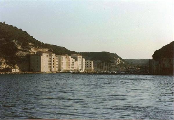 Bonifacio harbor: pale buildings along the quay, moored boats, cliffs behind