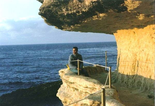 Man sitting on limestone rock terrace above the sea, shadow and light