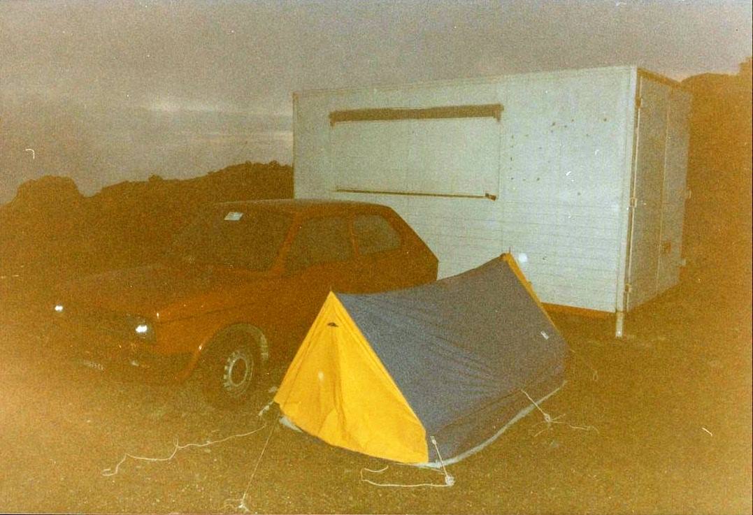 Tenda gialla e blu accanto a un'auto rossa e un rimorchio bianco