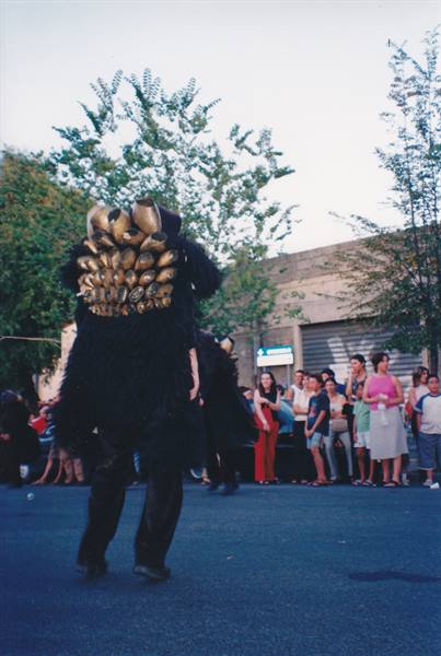 Mamuthone dancer in black mask with bronze bells before a crowd