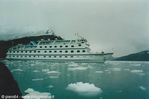 White cruise ship floating among icebergs and snowy mountains