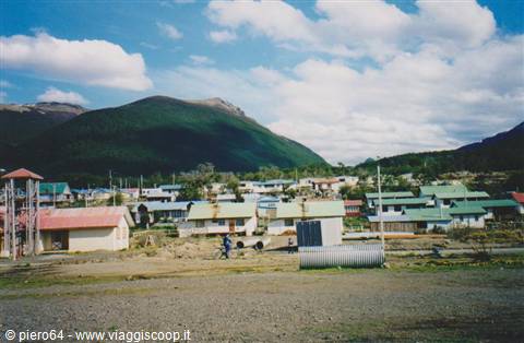 Village with colorful rooftop houses at the foot of forested mountains, cloudy sky