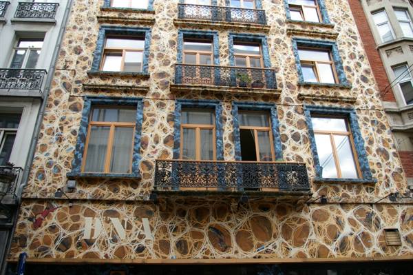 Building facade covered in fossil stone mosaic with blue windows, Brussels