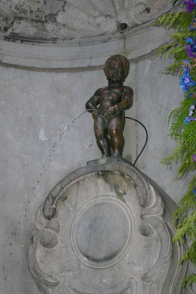 La statua del Manneken Pis getta acqua nella fontana di pietra a Bruxelles